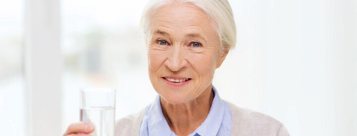 alte frau hält ein glas wasser